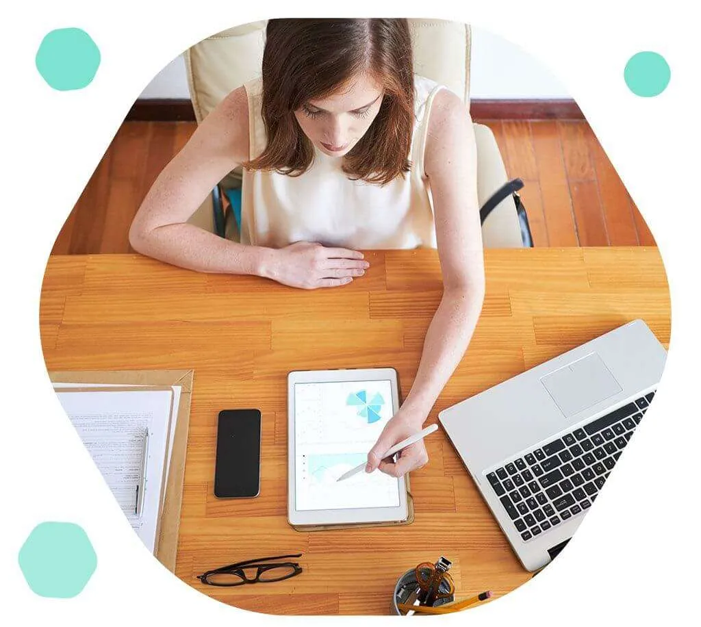 Women reviews designs on tablet sitting at desk